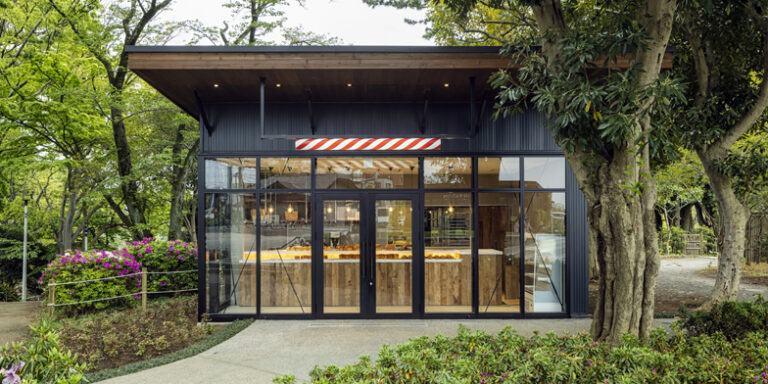 木々に囲まれたパンとエスプレッソと千葉公園の外観。黒い平屋の正面にガラス扉とパンの売り場が見える