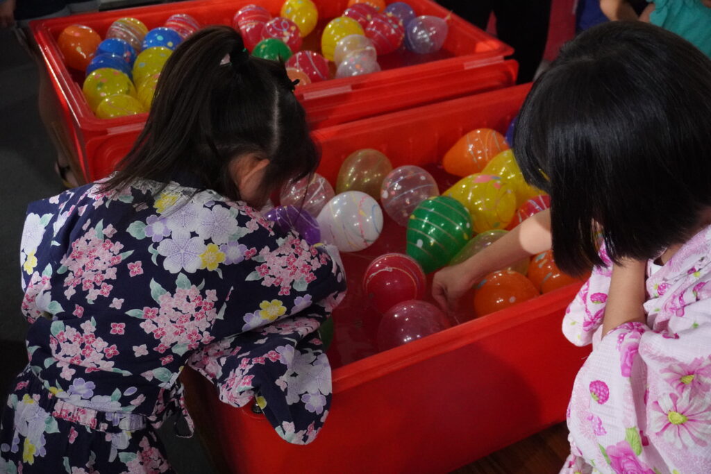 浴衣姿の子どもたちが水ヨーヨーすくいの縁日を楽しむ様子