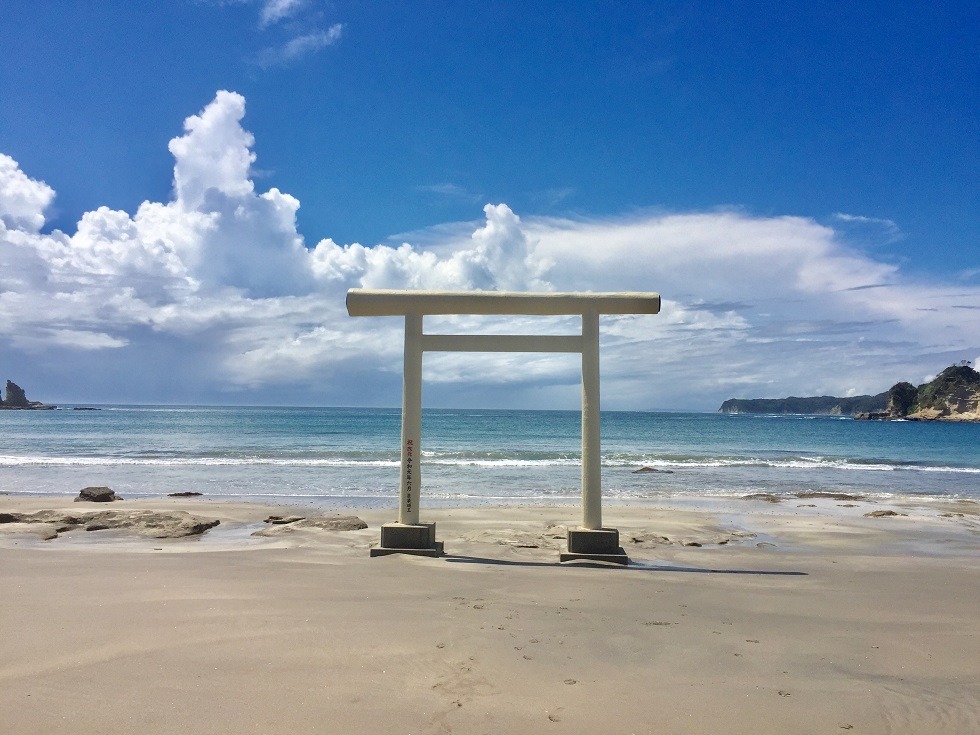 鵜原海岸の砂浜に立つ白い鳥居と青い海