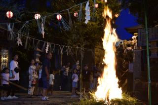 八重垣神社の駒まねで青竹を焼く炎と、それを見守る親子連れ