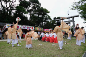洲崎神社の例祭で扇と御幣を掲げて輪になって舞うみのこ踊りの様子