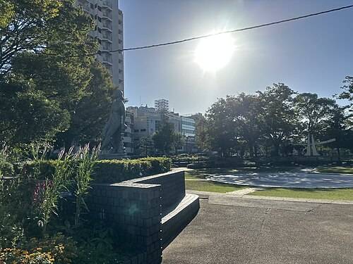 晴れた日の天沼弁天池公園。池と芝生、レンガ積みの低い壁、奥に彫像とマンションが見える