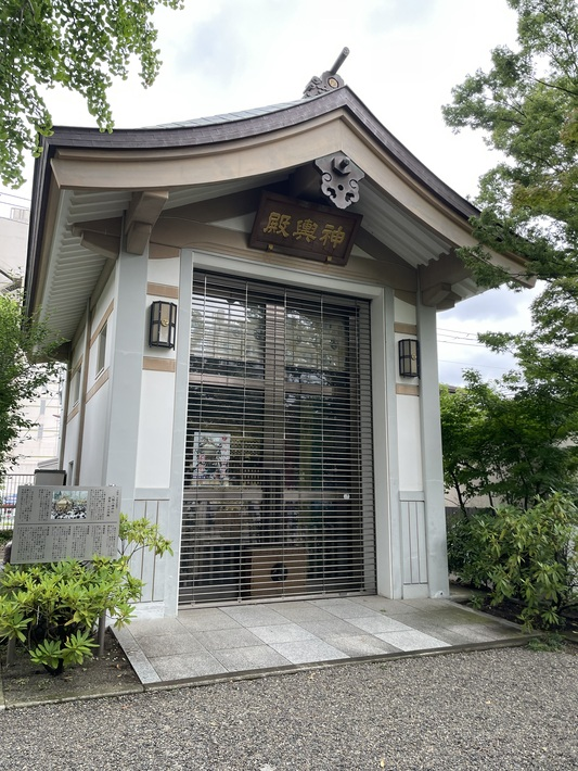八剱八幡神社の神輿殿の外観。「神輿殿」の扁額が掲げられ、脇に説明板が立つ