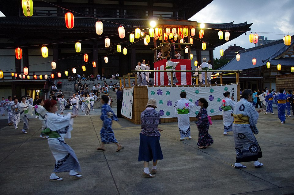 櫓の周りに集まって踊る盆踊りの人々と提灯