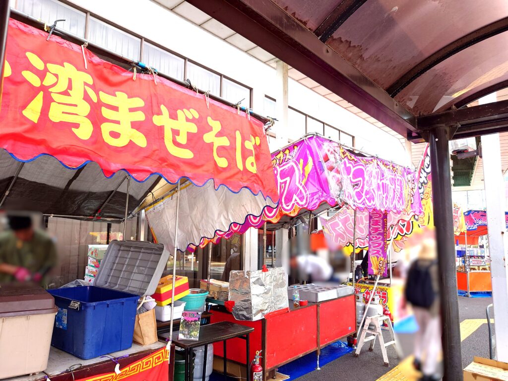 江戸川台納涼祭の商店街に並ぶ屋台。台湾まぜそばやたこ焼きののぼりが掲げられている