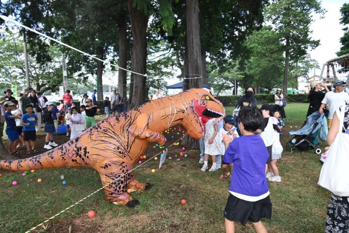 習志野駐屯地夏まつりの子ども広場。恐竜の着ぐるみと子どもたちがボールで遊ぶ様子