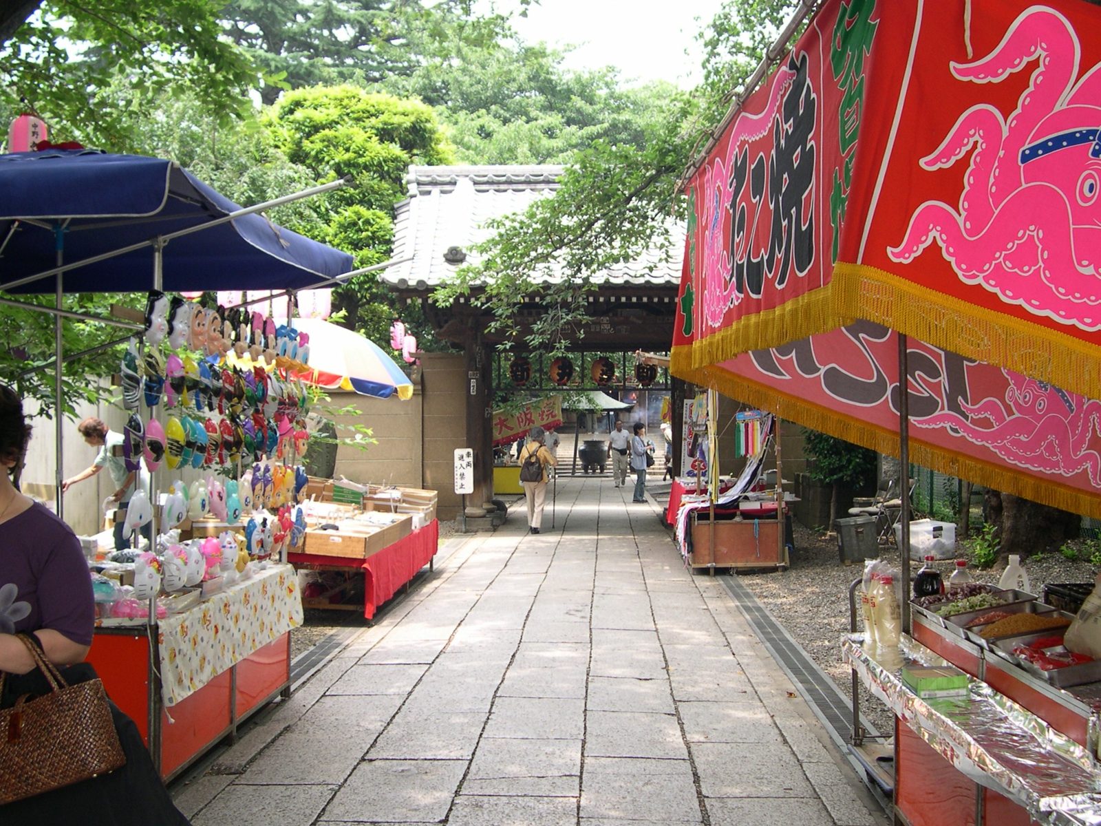 神社の参道の両側にたこ焼きやお面などの屋台が並ぶ縁日の様子