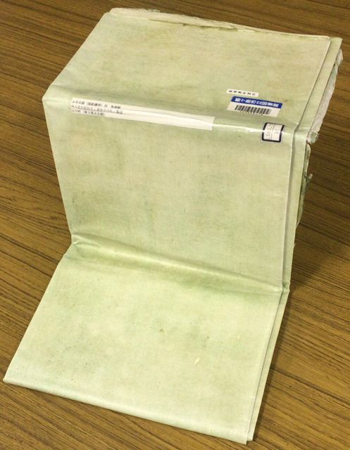 木の机の上に折り畳んで置かれた、薄い緑色をした和紙の大きな一枚