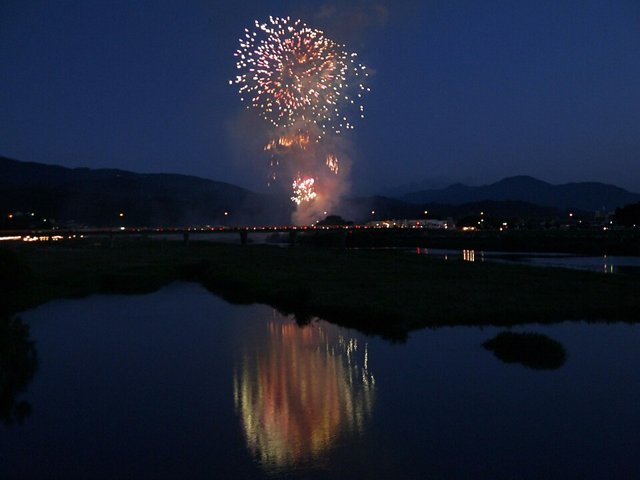 川沿いの夜空に上がる打ち上げ花火のイメージ