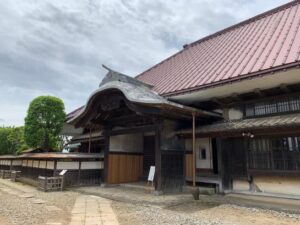 旧井上家住宅の母屋を斜めから見たところ。唐破風の玄関と赤い大屋根