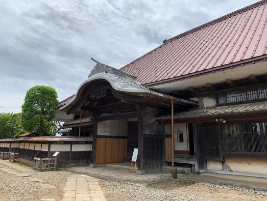 旧井上家住宅の母屋を斜めから見たところ。唐破風の玄関と赤い大屋根