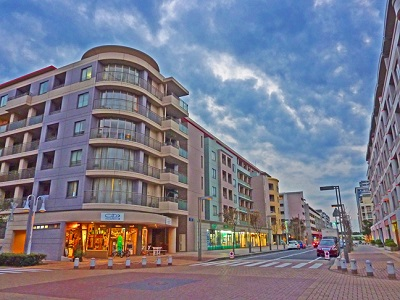 夕暮れの幕張ベイタウンの通り。1階に店舗が入る曲面バルコニーのマンションとレンガ敷きの歩道が続く