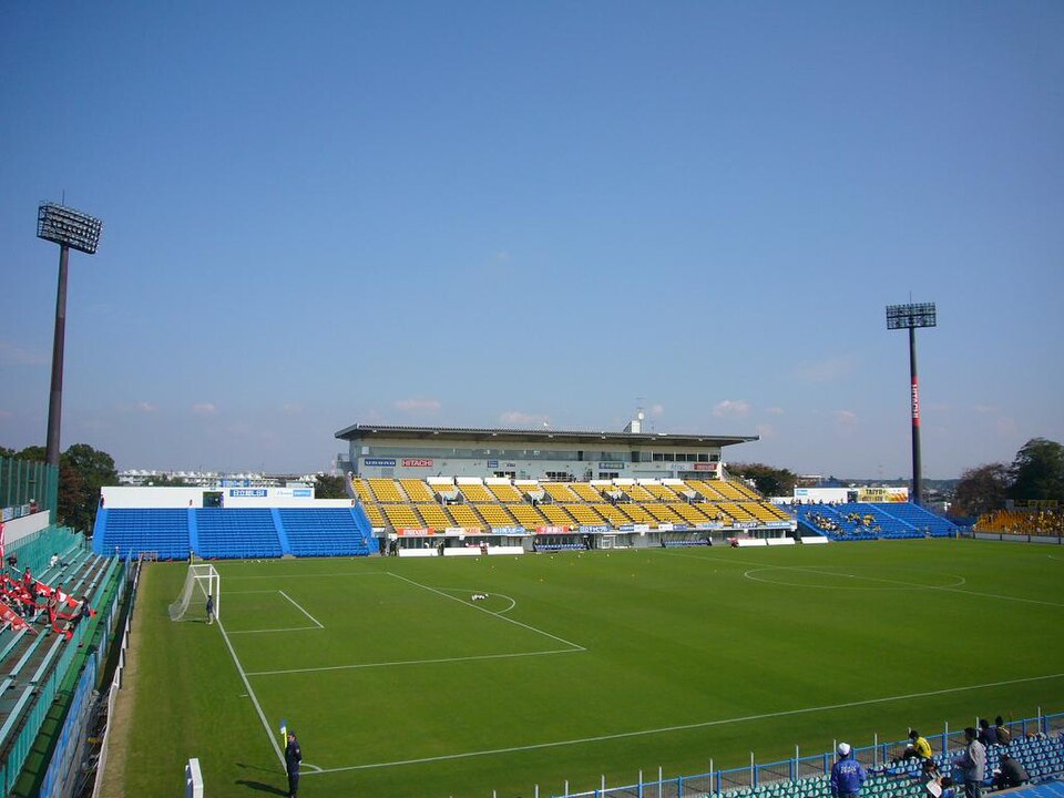 青空の下の三協フロンテア柏スタジアム（日立柏サッカー場）のピッチとメインスタンド