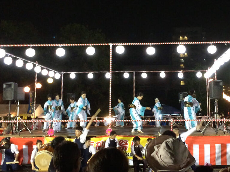 夜の真砂夏祭りの盆踊りステージ。浴衣姿の踊り手と提灯、手前で和太鼓を叩く子どもたち