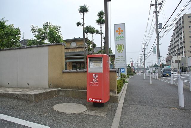 篠籠田地区の歩道に立つ赤い郵便ポストと、その先に続く住宅地の通り