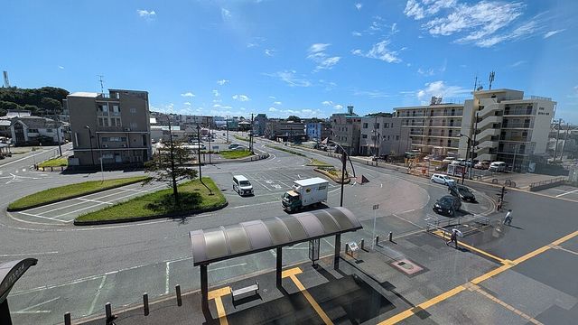 快晴の空の下、バス停の上屋やタクシー乗り場が並ぶ袖ケ浦駅南口のロータリーを跨線橋の上から見下ろした様子
