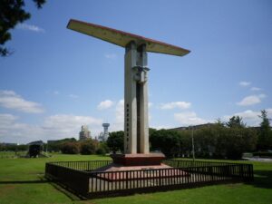 稲岸公園に立つ民間航空発祥之地の記念塔。翼の形をした白いモニュメントと芝生広場