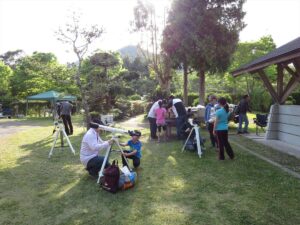 内浦山県民の森の芝生広場に望遠鏡を据える参加者たち