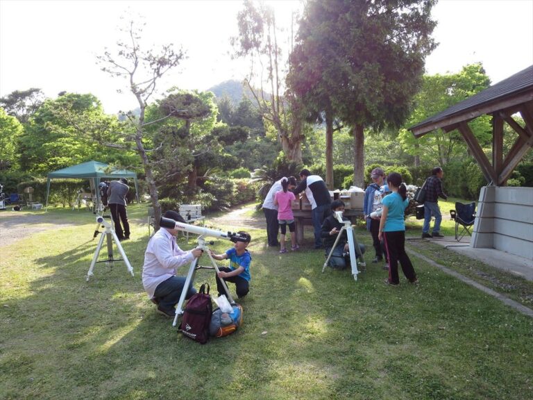 内浦山県民の森の芝生広場に望遠鏡を据える参加者たち