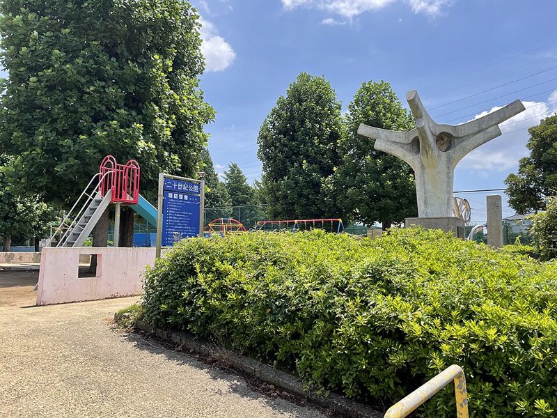 松戸市の二十世紀公園。梨の木をかたどったコンクリート製のモニュメントと「二十世紀公園」の案内板、奥に遊具が見える