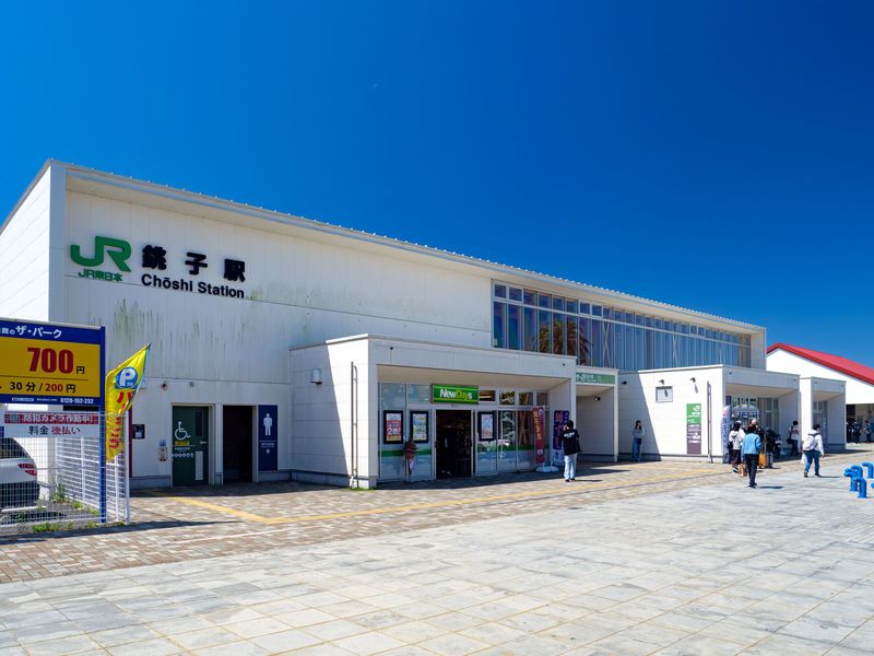JR銚子駅の駅舎外観。青空の下、駅前広場に人が歩いている
