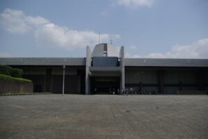 千葉県文化会館の正面。低く横に広がる建物の中央に台形の塔屋があり、手前に広い石張りの前庭
