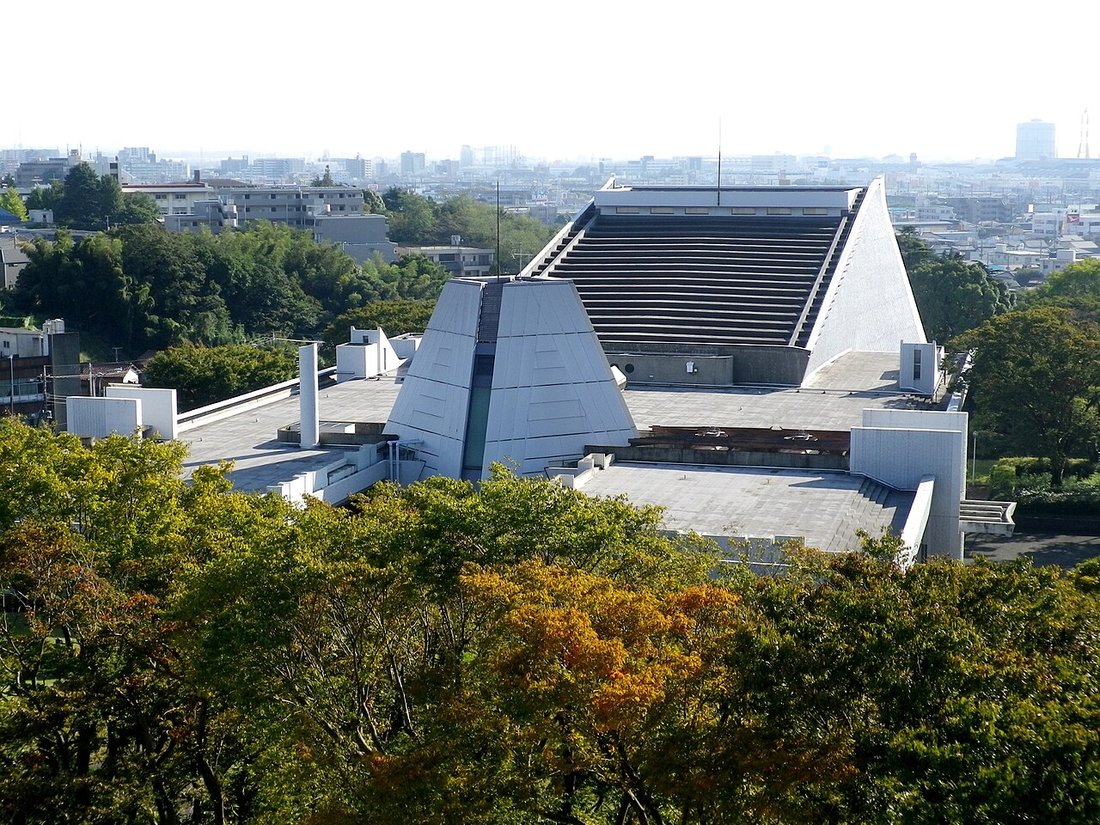 千葉県文化会館を高台から見下ろした風景。台形の大屋根と階段状の屋根が並び、背後に千葉市街地が広がる