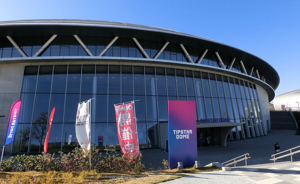 TIPSTAR DOME CHIBAの入口。円形のガラス張りの建物の前に「TIPSTAR DOME」と書かれた看板とのぼりが立っている