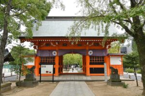 葛飾八幡宮の朱塗りの随神門を正面から見た写真。紫の幕に白い菊紋、左右に狛犬