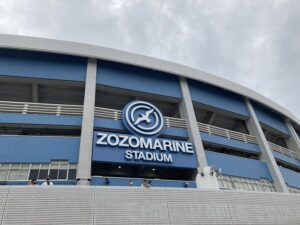 ZOZOMARINE STADIUMのロゴと球団マークが掲げられた青い外壁を見上げたZOZOマリンスタジアムの外観
