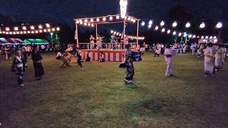 真砂一丁目団地の夏祭りで提灯に囲まれたやぐらを囲んで踊る参加者