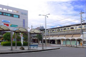 JR茂原駅南口の駅前広場。アーチ屋根のバス待合所が並び、右奥に高架の駅舎と停車中の黄色い帯の電車