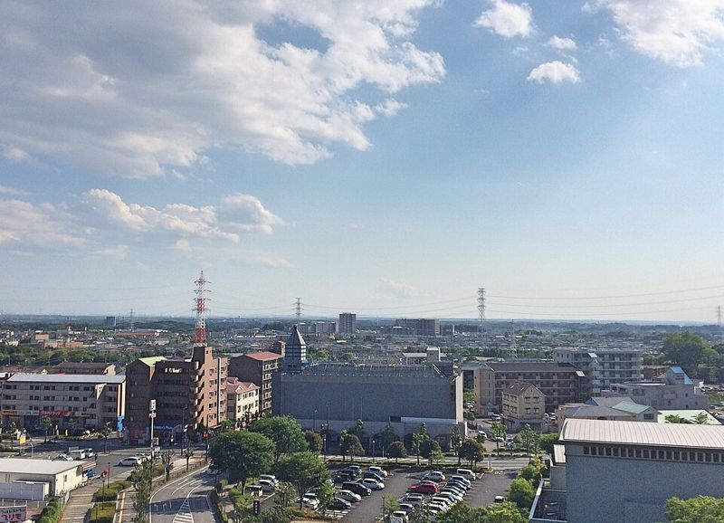 おゆみ野の街並みを高い場所から見下ろした写真。低層のマンションや住宅、送電鉄塔、駐車場が広がっている