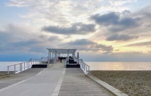稲毛海浜公園のいなげの浜。白い砂浜から海へ向かってウッドデッキが延び、その先に白い屋根の建物が立っている