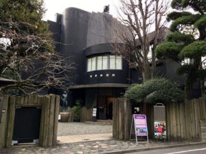 朝倉彫塑館の黒い外観と、門の内側に立つ人物像