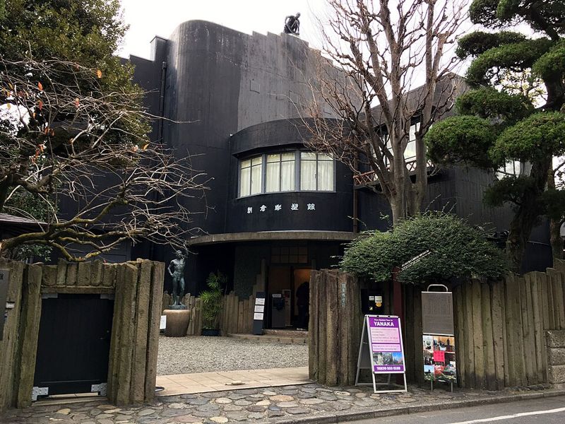 朝倉彫塑館の黒い外観と、門の内側に立つ人物像