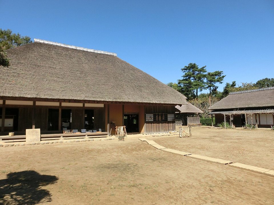 房総のむらの下総の農家。横に長い茅葺き屋根の母屋の前に広い土の庭があり、右奥にも茅葺きの建物が見える