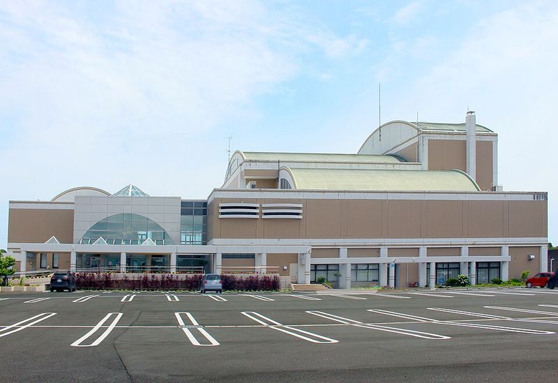長生村文化会館の外観。曲面屋根のホール棟の前に広い平面駐車場が広がっている