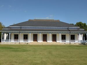 重要文化財・旧学習院初等科正堂の外観。白い列柱と手すりが並ぶ正面ポーチと、芝生の前庭が広がっている