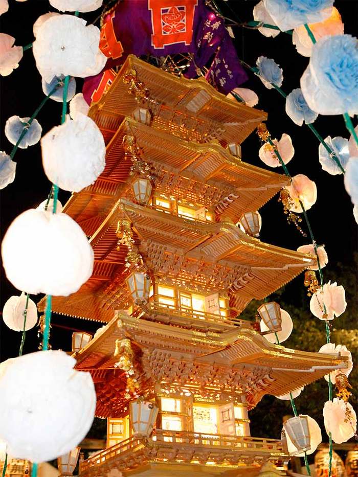 灯りがともった五重塔形の万灯と桜の造花