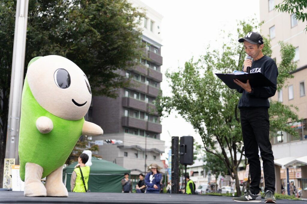 屋外ステージに立つ杉並区のキャラクターなみすけと司会者