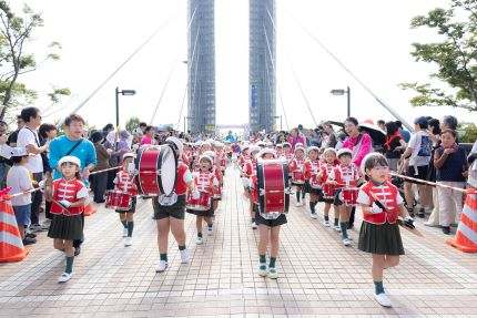 木場公園大橋を鼓笛隊の子どもたちが行進する江東区民まつりのオープニングパレード