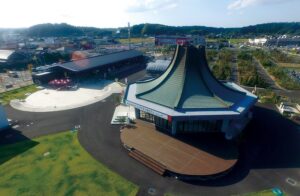 道の駅みのりの郷東金を上空から見た写真。駐車場と複数の棟、緑花木市場の敷地が広がる