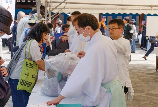 袋に入れた人形を受付で神職に託す参拝者