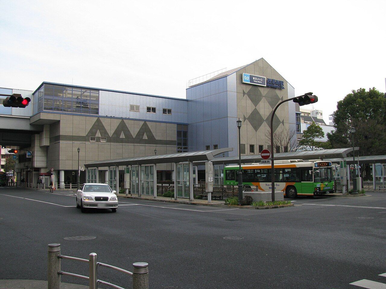 西葛西駅の駅舎全景。手前の道路に面してバス乗り場の屋根が続き、都営バスが停まっている