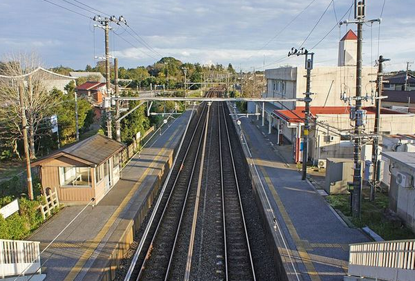 八積駅のホーム。相対式2面2線の線路をまたぐ跨線橋から見下ろした眺めで、片側に小さな待合室が建つ