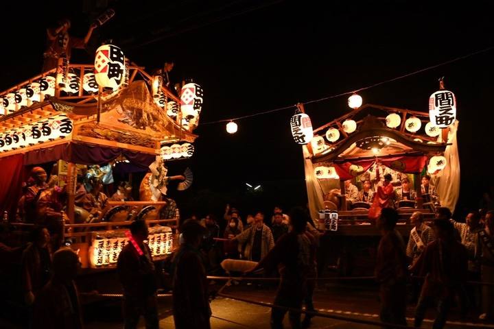 夜の城下町で、提灯をともした田町と間之町の御神酒所が並び、囃子台の上で人が踊っている