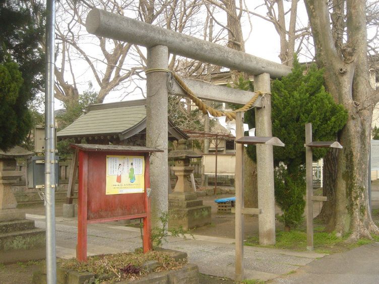 蘇我比咩神社の石の鳥居と、その脇に立つ由緒書きの赤い案内板