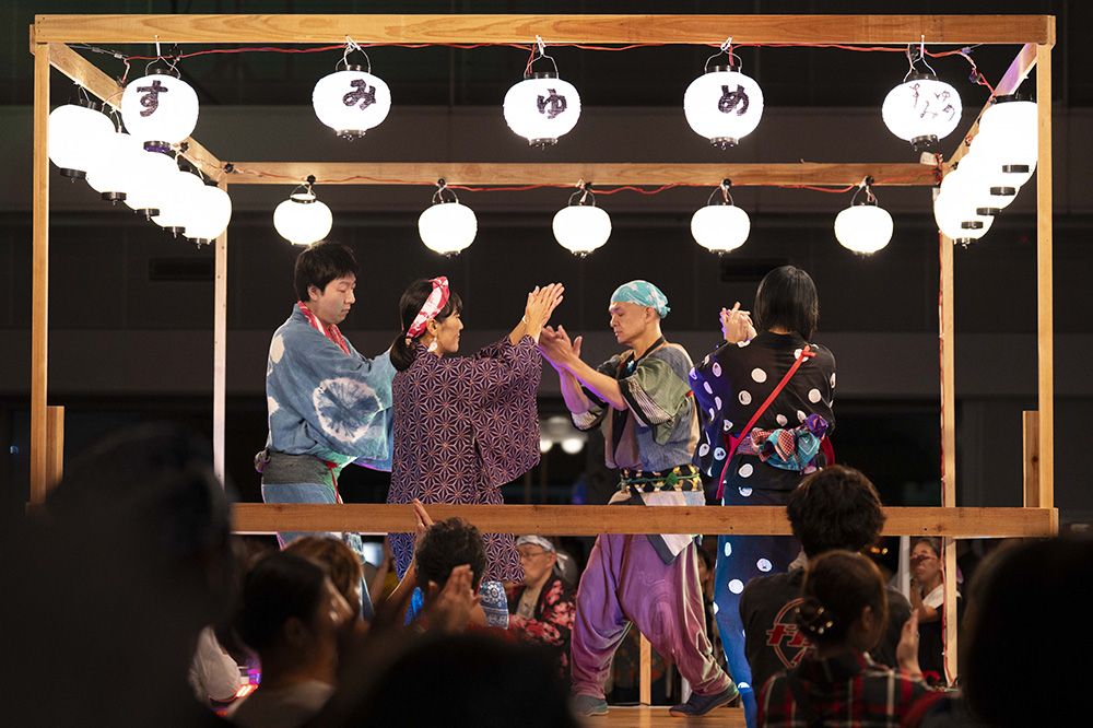 すみゆめの提灯を下げたやぐらの上で歌う出演者