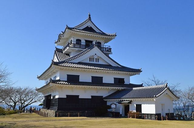 城山公園山頂広場に立つ館山城の天守。芝生の広場から見上げた白壁の三層の建物